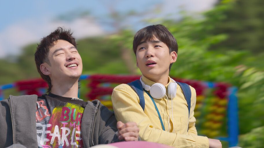 Two young men enjoying a ride together outdoors in a cheerful scene from Move to Heaven.